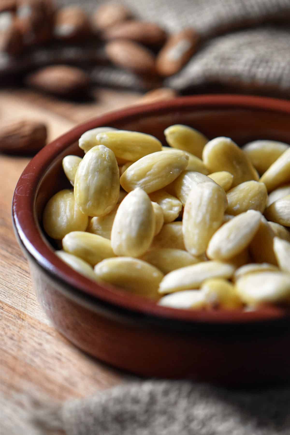 A round ceramic dish filled with blanched almonds.