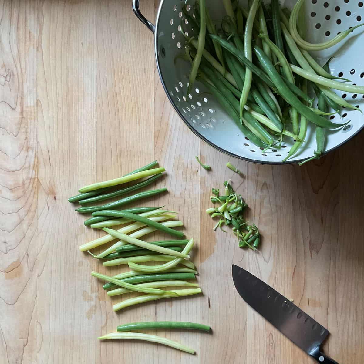 Trimmed fresh green beans on a wooden cutting board.