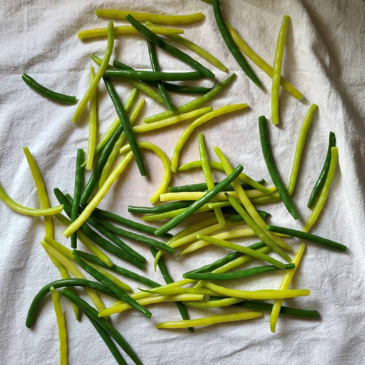 Yellow and green beans on a white tea towel.