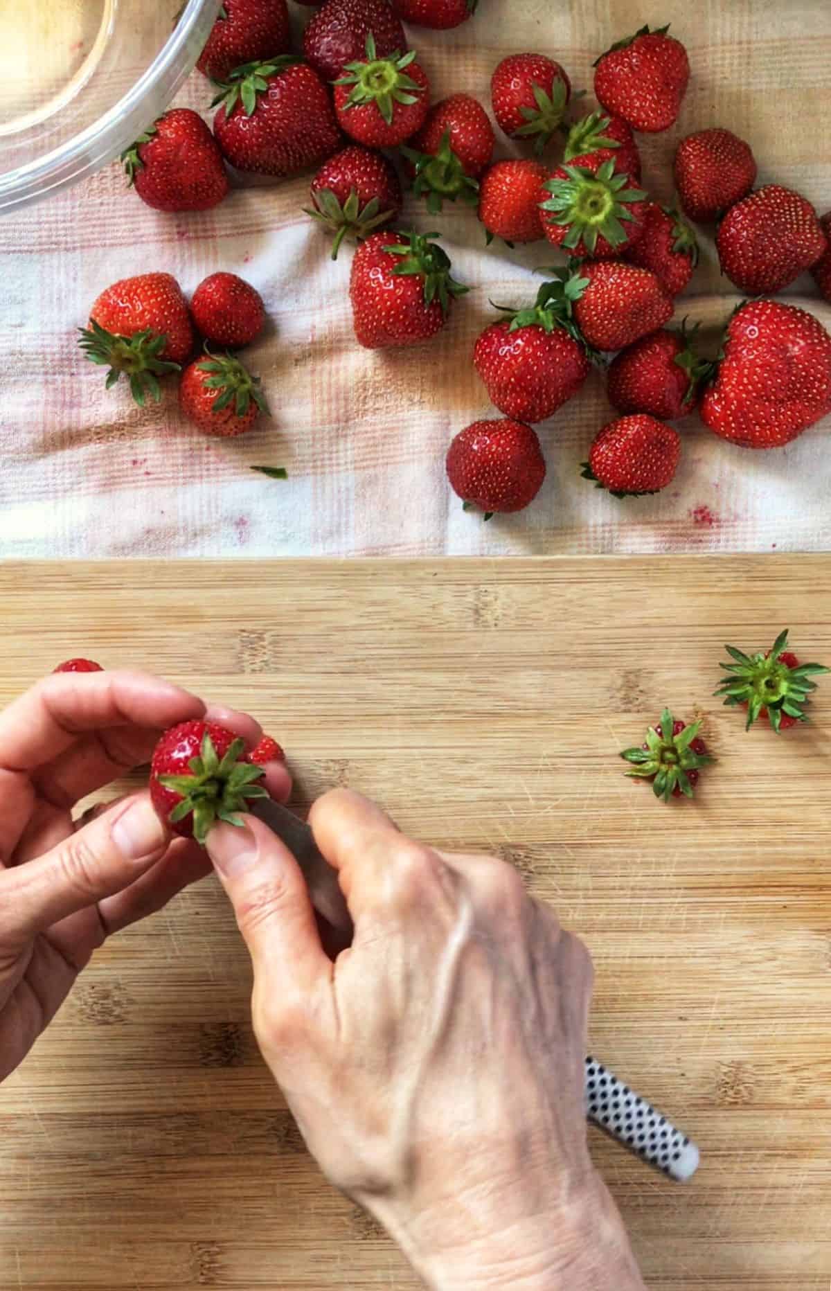 One of the steps on how to freeze strawberries involves the removal of the hull. In this picture, a paring knife is used.