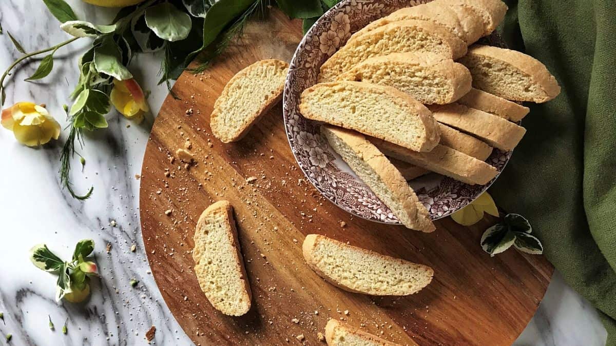 Sliced biscotti surrounded by fresh lemons, and green leaves.