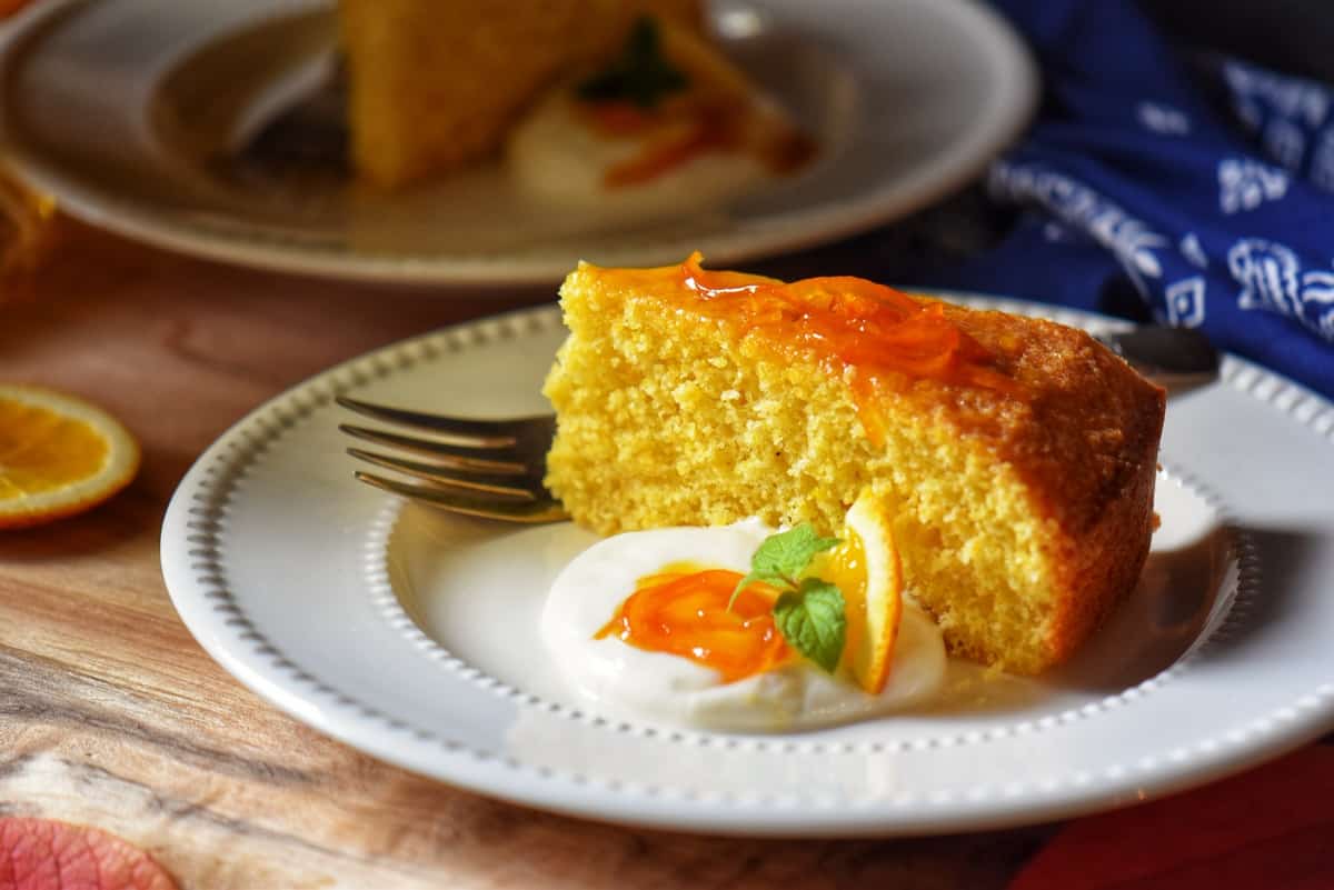 A slice of orange cake garnished with orange syrup and whipped ricotta.