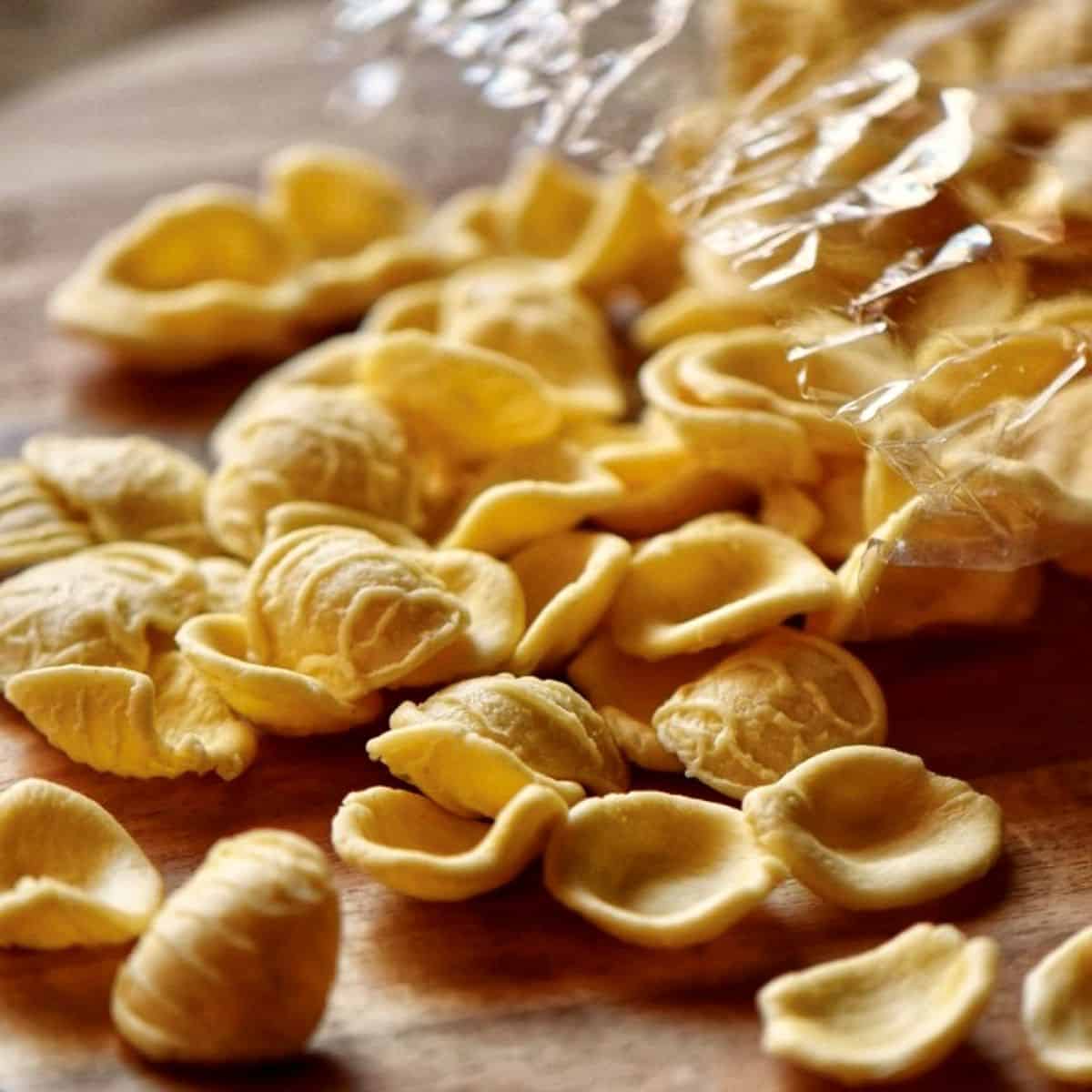 The dry form of the orecchiette pasta on a wooden board.
