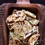 A large decorative wooden serving platter with dozens of thin biscotti.