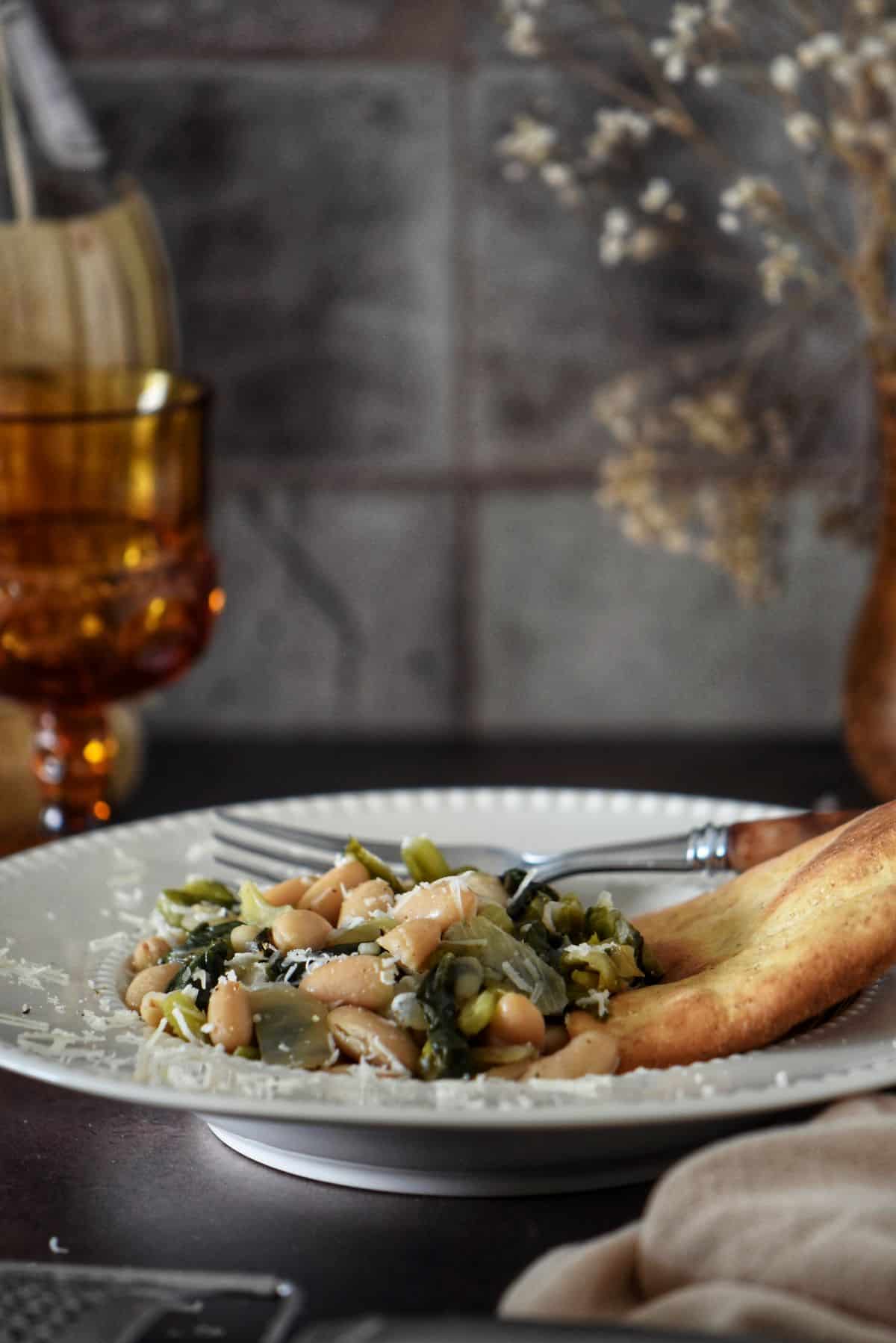 Beans and greens in a white soup bowl.