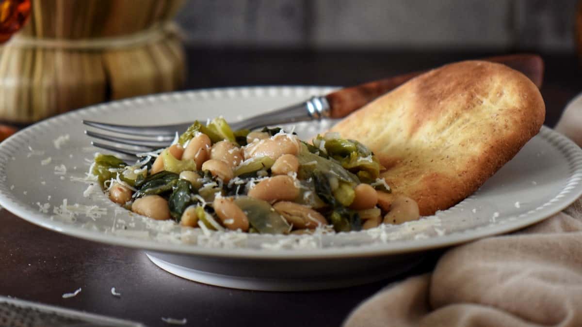 Greens and beans garnished with grated romano cheese.