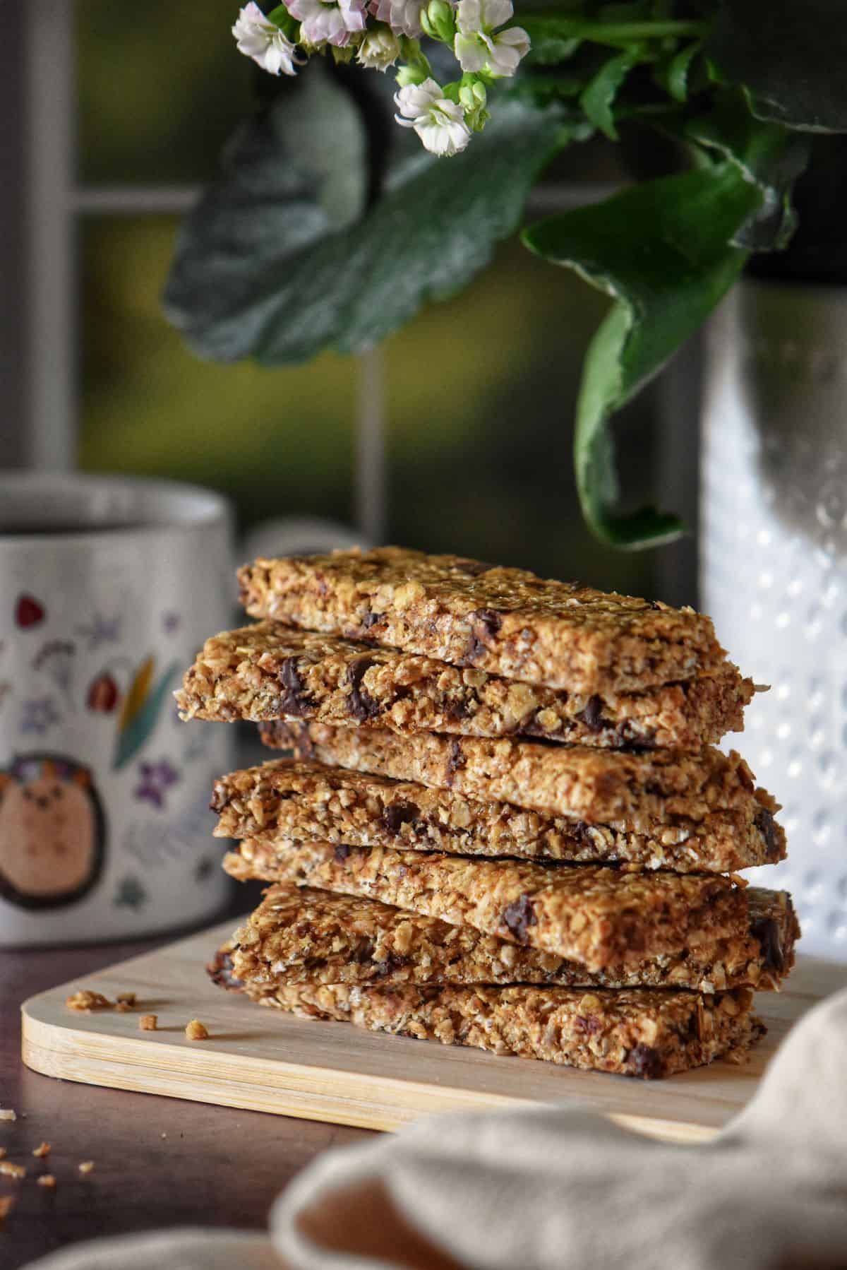 A stack of granola bars next to a cup of coffee.