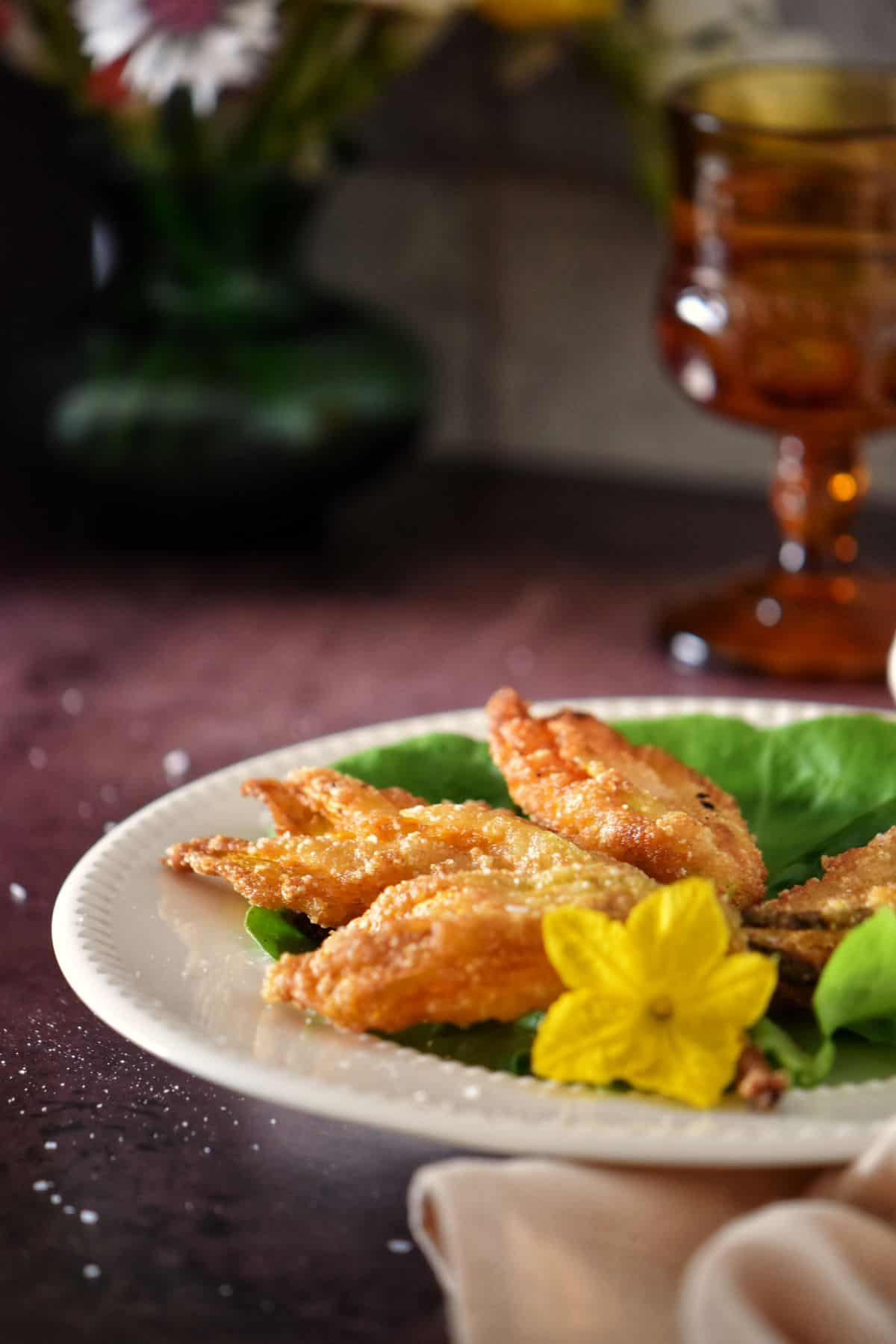Fried zucchini flowers on a white serving dish.