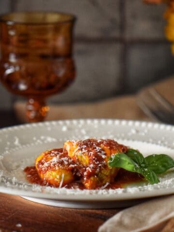 Ricotta-stuffed zucchini flowers smothered with marinara sauce and garnished with grated cheese.