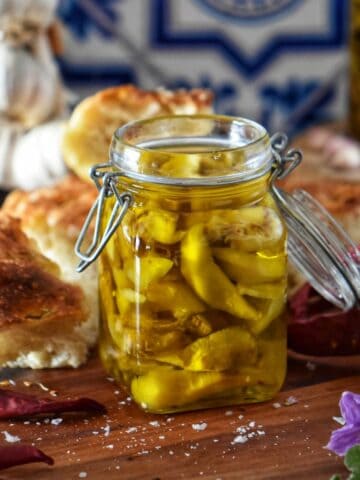 A jar of melanzane sott'olio (pickled aubergines) surrounded by focaccia bread and chili peppers.