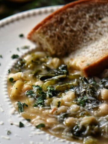 Escarole and beans served with a slice of whole wheat bread.
