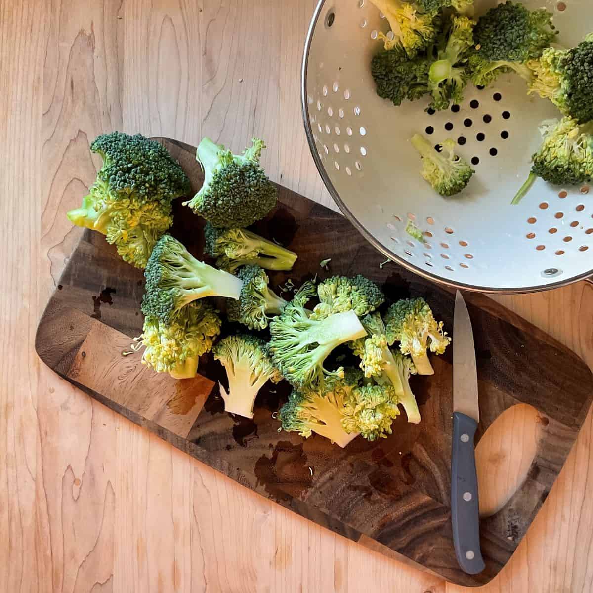 Cut up broccoli on a wooden board.