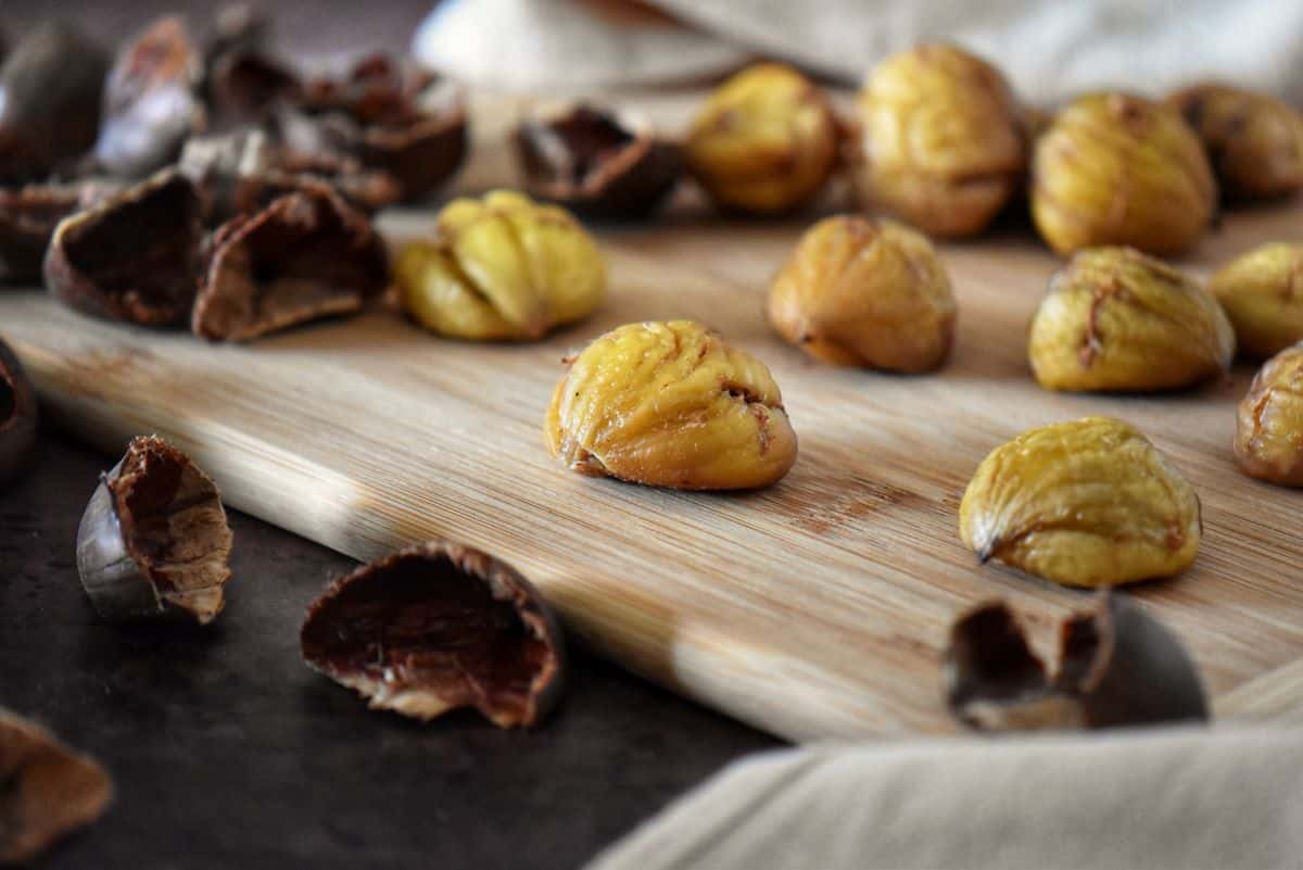 Shelled chestnuts on a wooden cutting board.