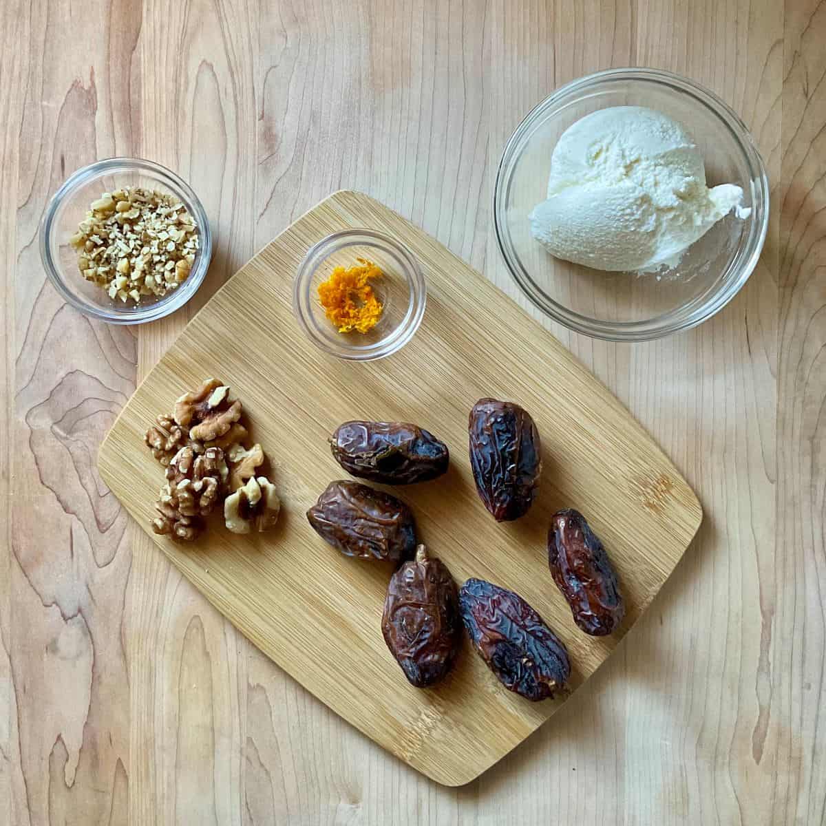 Ingredients to make stuffed dates with ricotta on a wooden board.