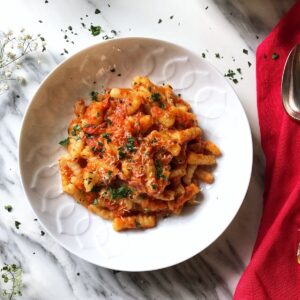 Red pepper sauce with cavatelli in a white bowl.
