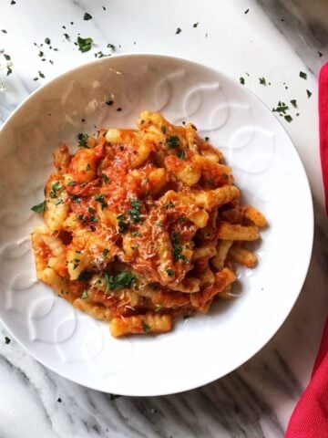 Red pepper sauce with cavatelli in a white bowl.