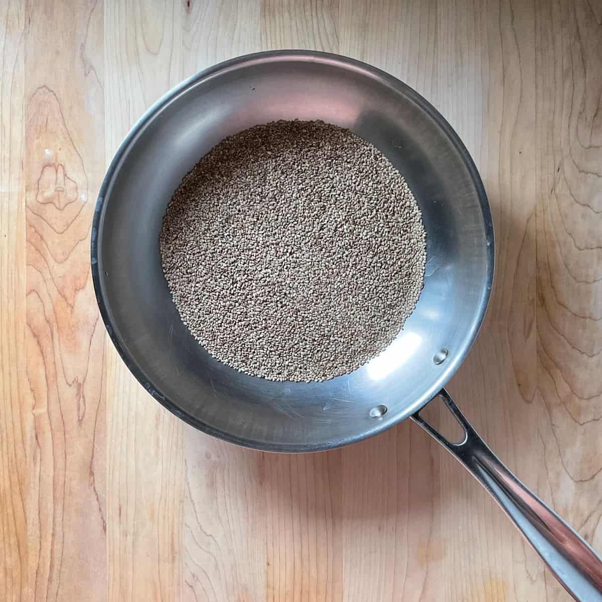 Sesame seeds toast in a skillet.