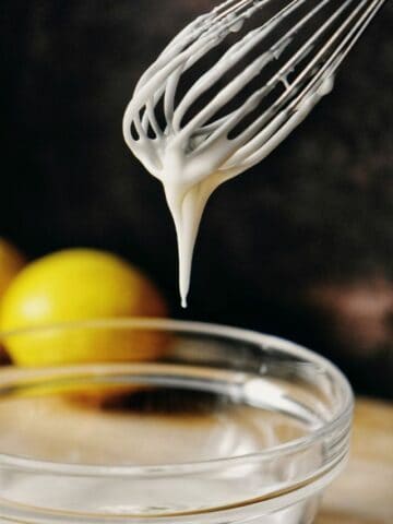 Lemon glaze dripping down a whisk.