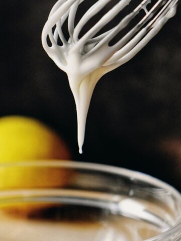 Lemon glaze dripping down a whisk.