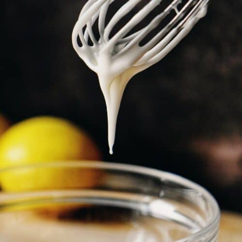 Lemon glaze dripping down a whisk.