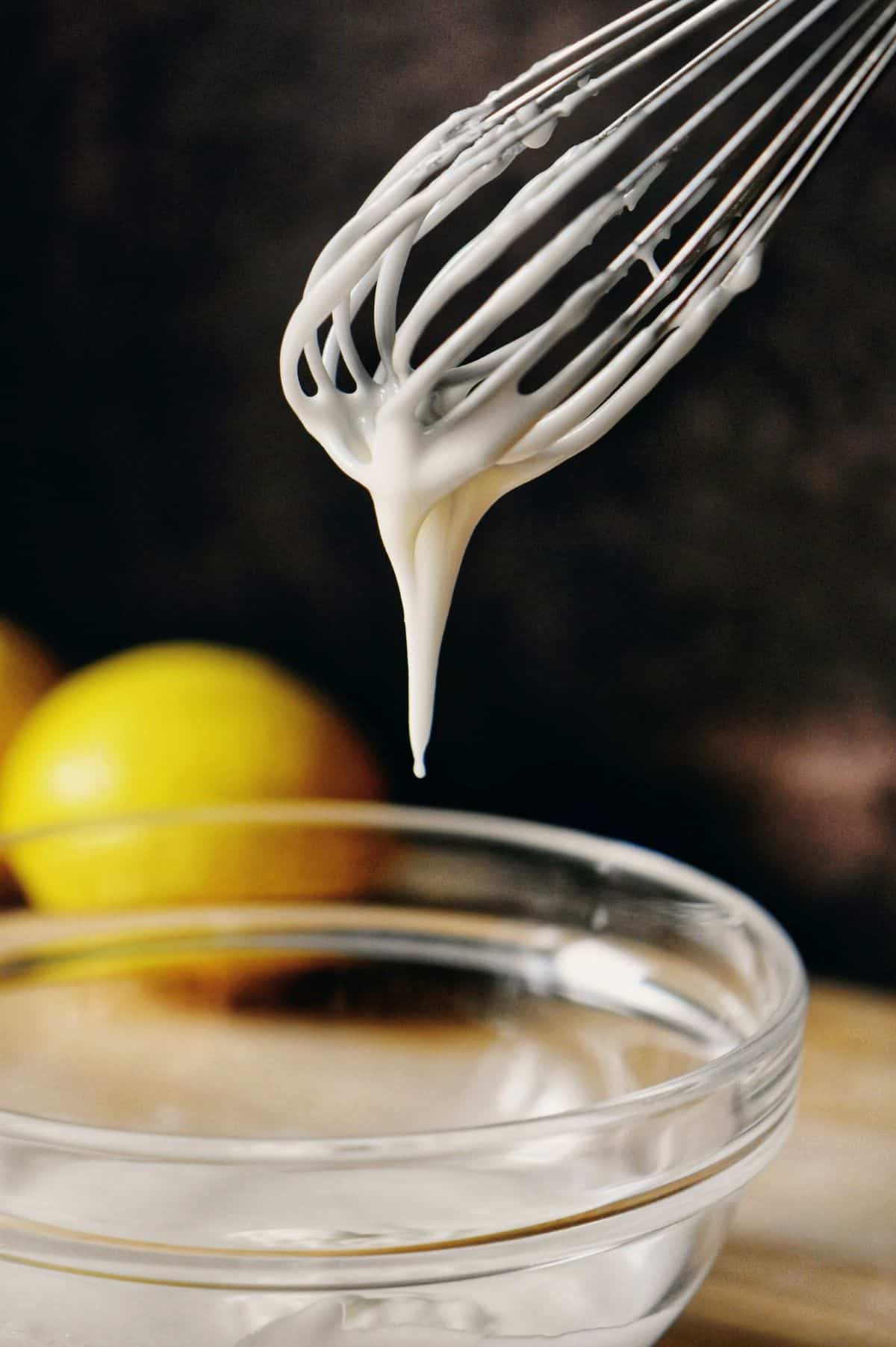 Lemon glaze dripping down a whisk.