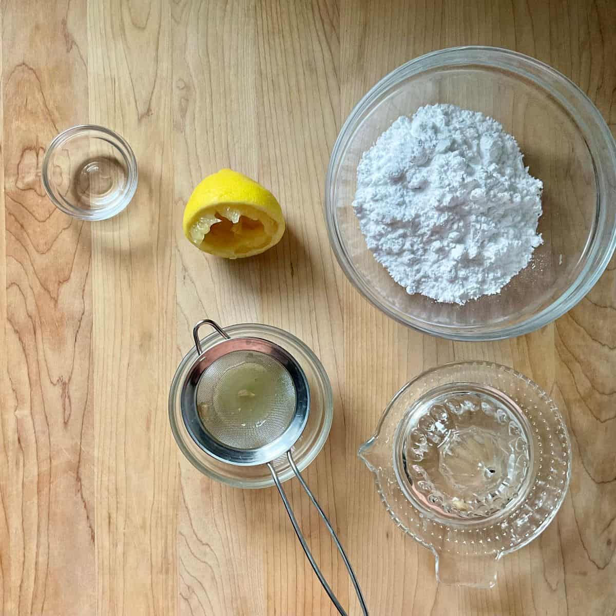 Ingredients to make lemon glaze icing includes sifted icing sugar and sieved lemon juice.