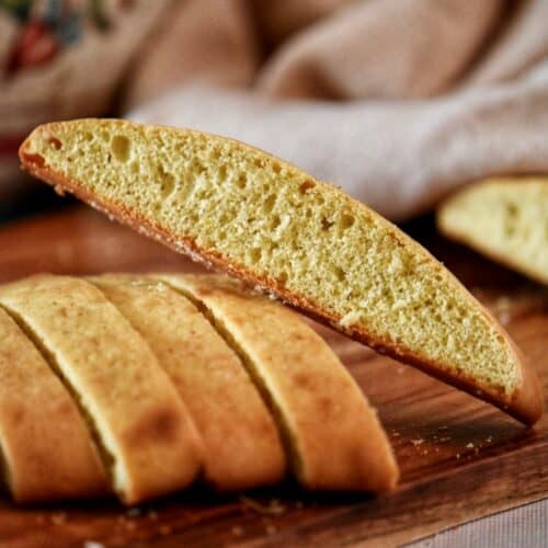 Sliced anisette sponge cookies on a wooden board.