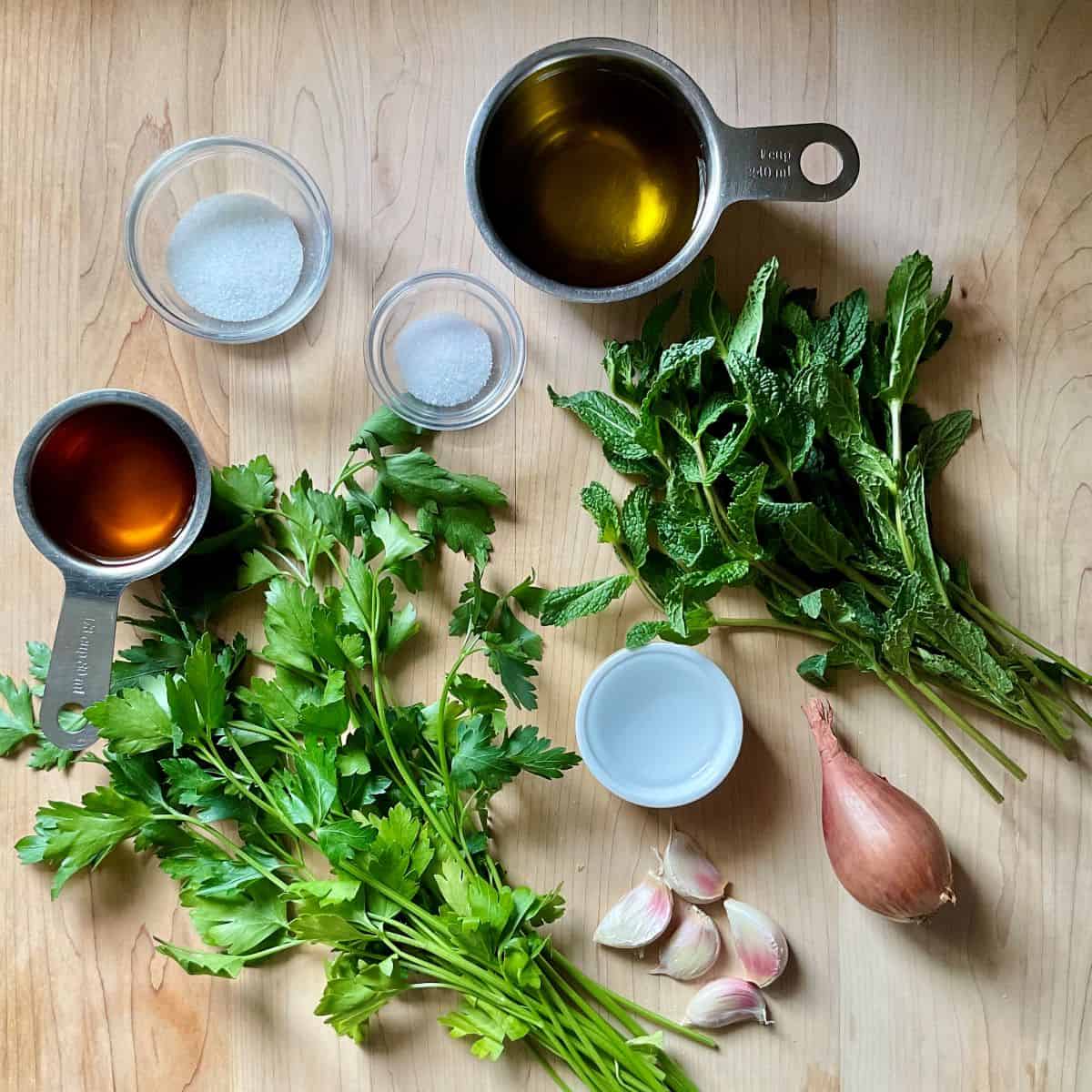 Ingredients to make a green herb sauce on a wooden board.