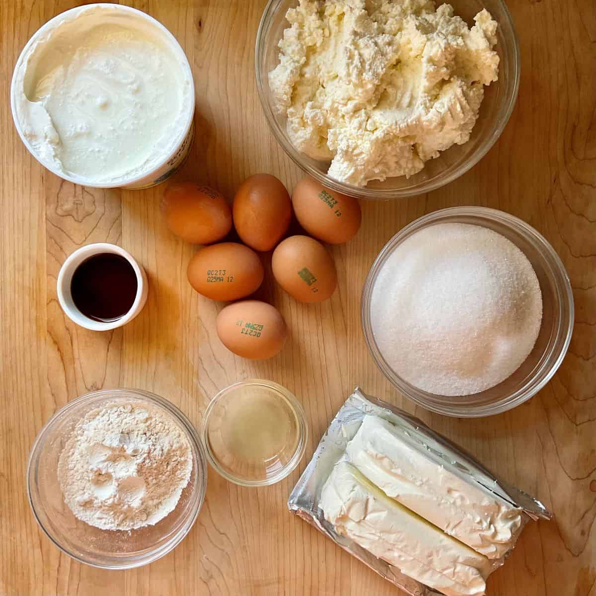 Ingredients to make an Italian cheesecake on a wooden board including ricotta and eggs.
