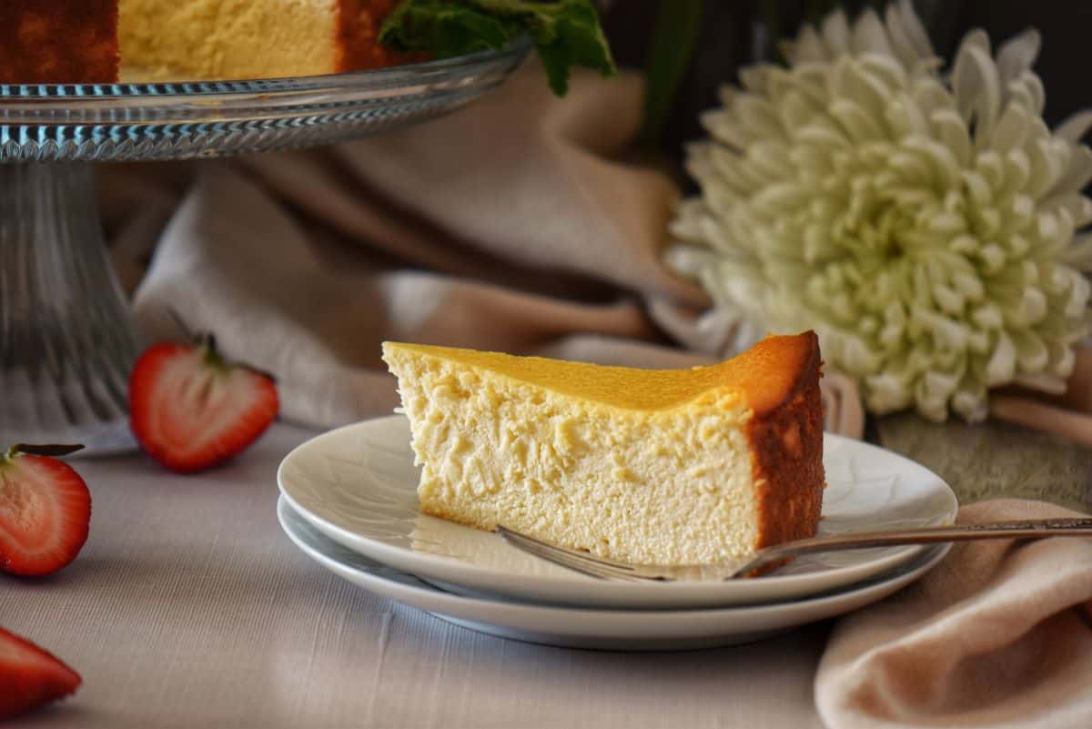 A plain slice of ricotta cheesecake on a white plate.