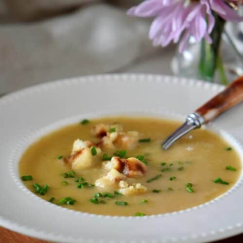 A white bowl of creamy potato leek soup.