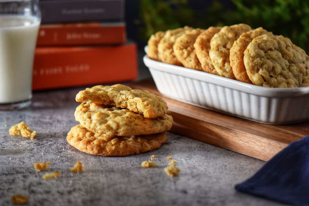 Small stack of coconut oatmeal cookies with a bite taken from the top cookie, revealing the chewy texture inside.