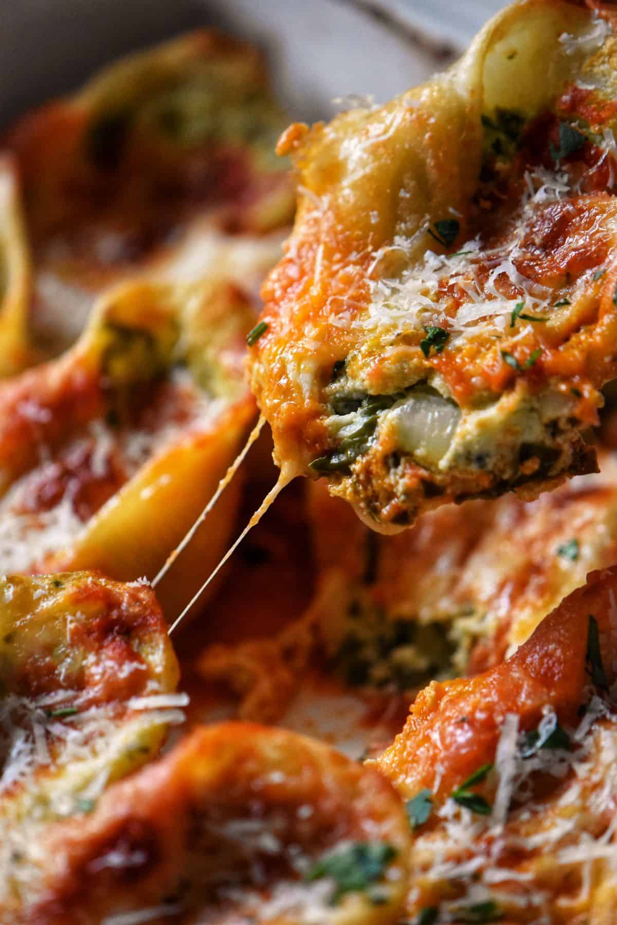 A single giant stuffed pasta shell being pulled upwards with a cheesy string pull. 