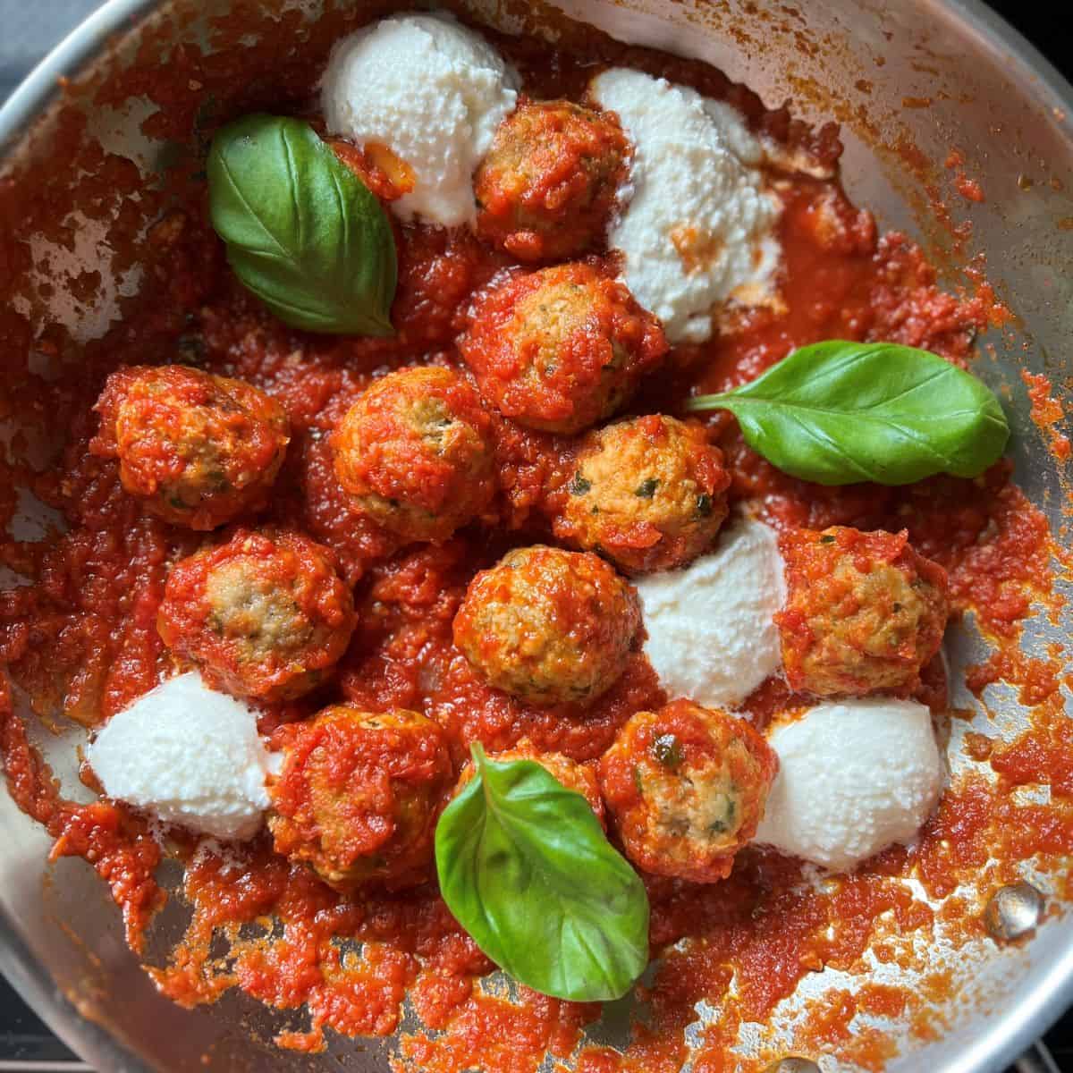 Tender ricotta meatballs with dollops of creamy ricotta and fresh basil leaves, nestled in a rich tomato sauce.