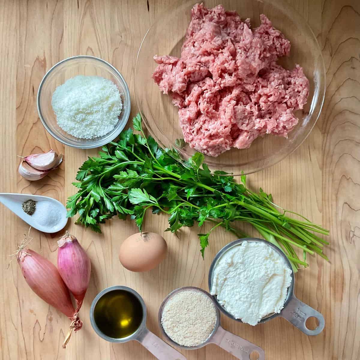 Ingredients on a wooden board to make veal and ricotta meatballs.