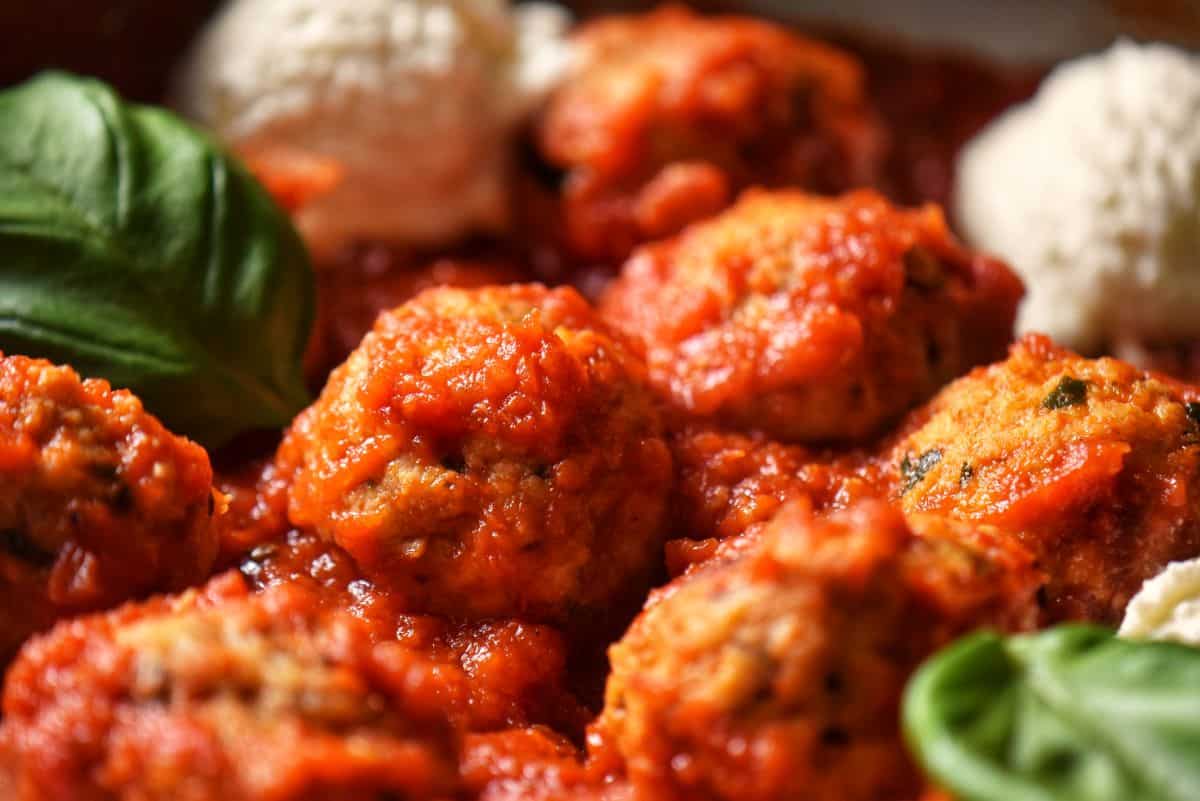 A close up of tender ricotta cheese meatballs in a marinara sauce.