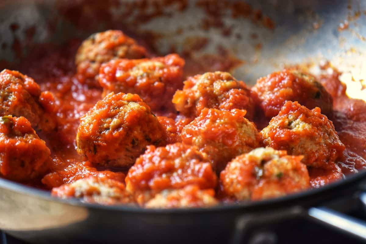 Ricotta cheese meatballs in a pan with marinara sauce.