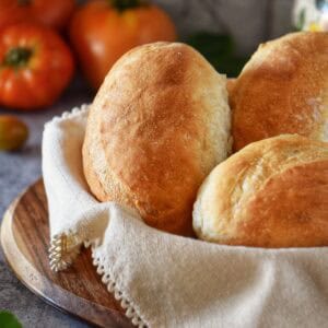 Freshly baked Italian sandwich rolls in a basket.