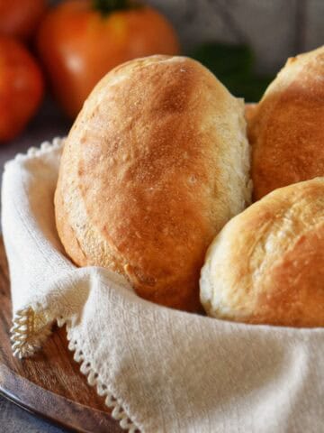 Freshly baked Italian sandwich rolls in a basket.