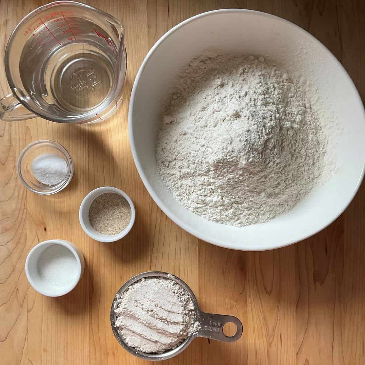 Ingredients for Italian pagnotta bread measured out on a counter, including flour, yeast, water, and salt.