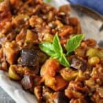 Close-up view of eggplant caponata appetizer, a Sicilian-inspired dish with eggplant, tomatoes, olives, and capers.