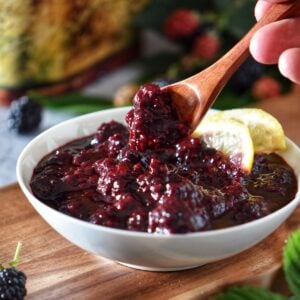 A spoonful of thick blackberry compote lifted from a bowl, highlighting the chunky fruit texture.