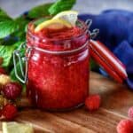 Raspberry compote in a mason jar with lemon garnish.