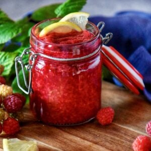 Raspberry compote in a mason jar with lemon garnish.