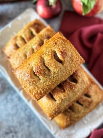 Fresh baked apple hand pies with golden egg wash finish and coarse sugar cinnamon topping.