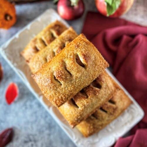 Fresh baked apple hand pies with golden egg wash finish and coarse sugar cinnamon topping.