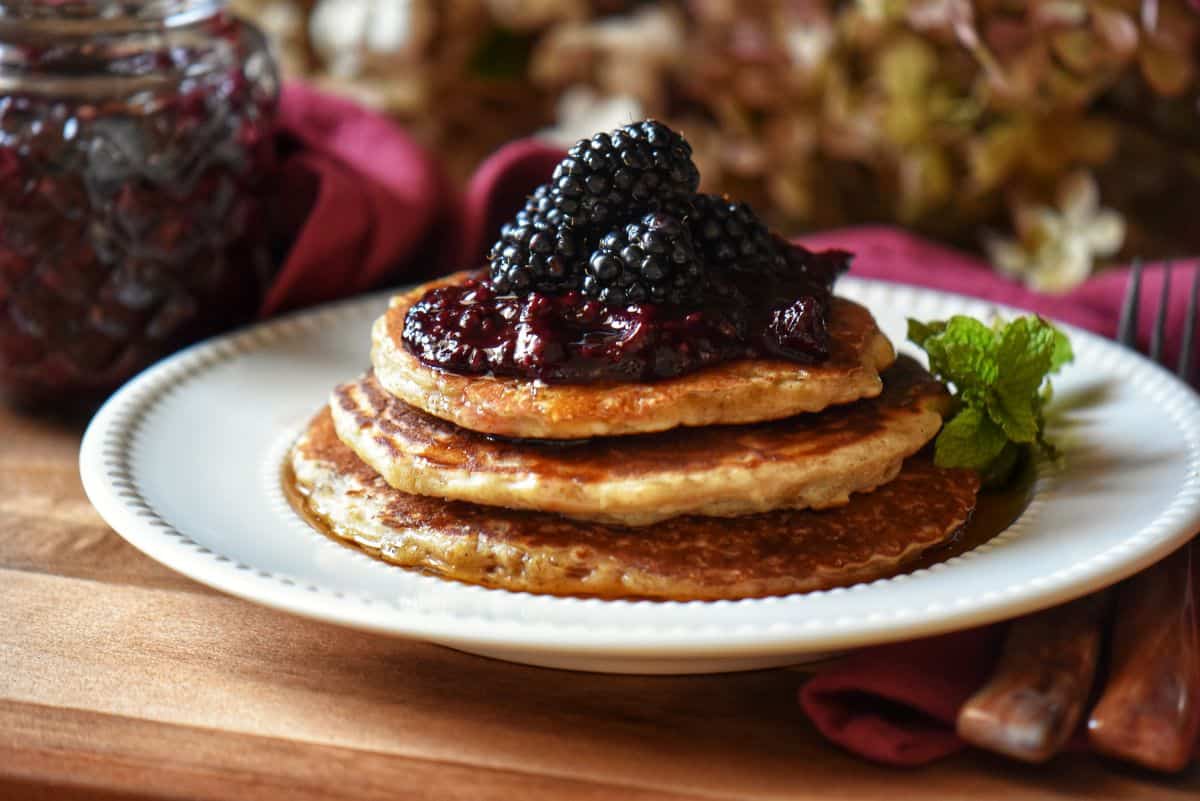 Oatmeal pancakes garnished with blackberry compote and fresh blackberries.