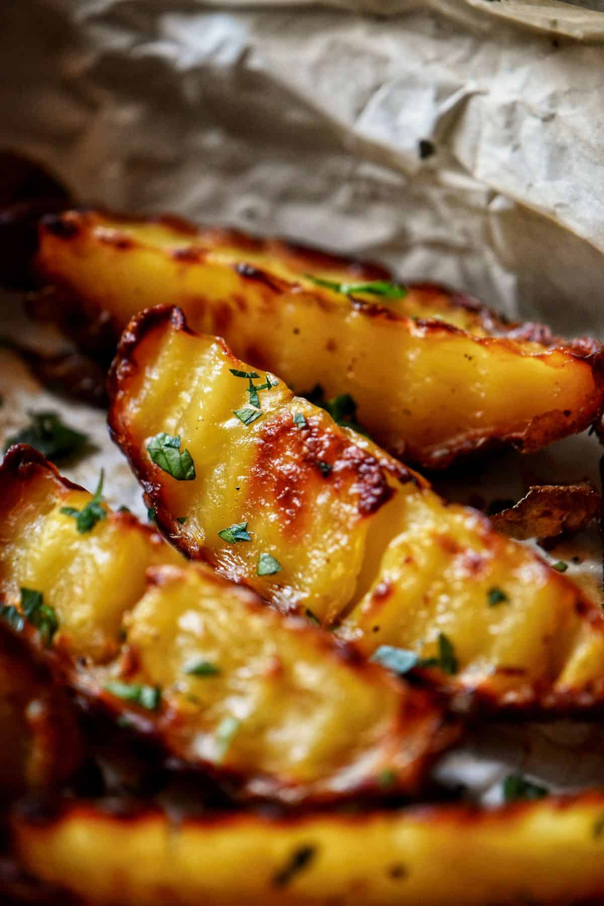 Golden, crispy baked potato wedges on a parchment-lined baking sheet.