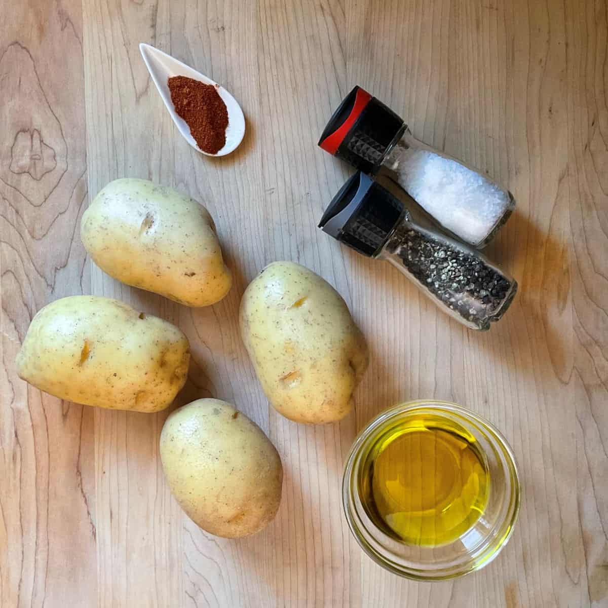 Ingredients for crispy baked potato wedges, including Yukon Gold potatoes, olive oil, salt, pepper, and paprika.