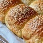 Freshly baked, golden soft dinner rolls with olive oil on parchment paper.